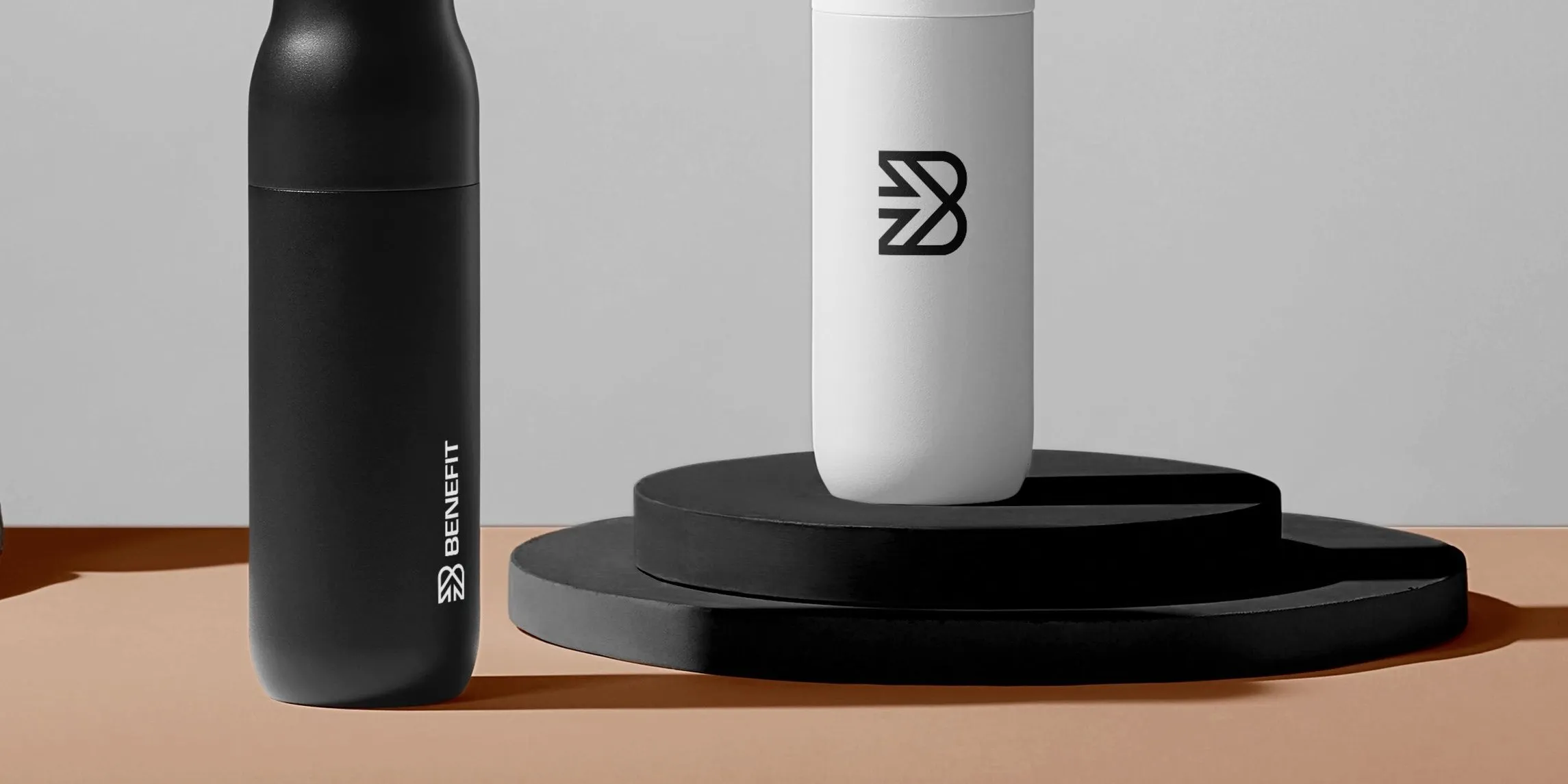 Zwarte en witte bidon met het beeldmerk van BeneFIT Studio op een sokkel. Door Fitbrand