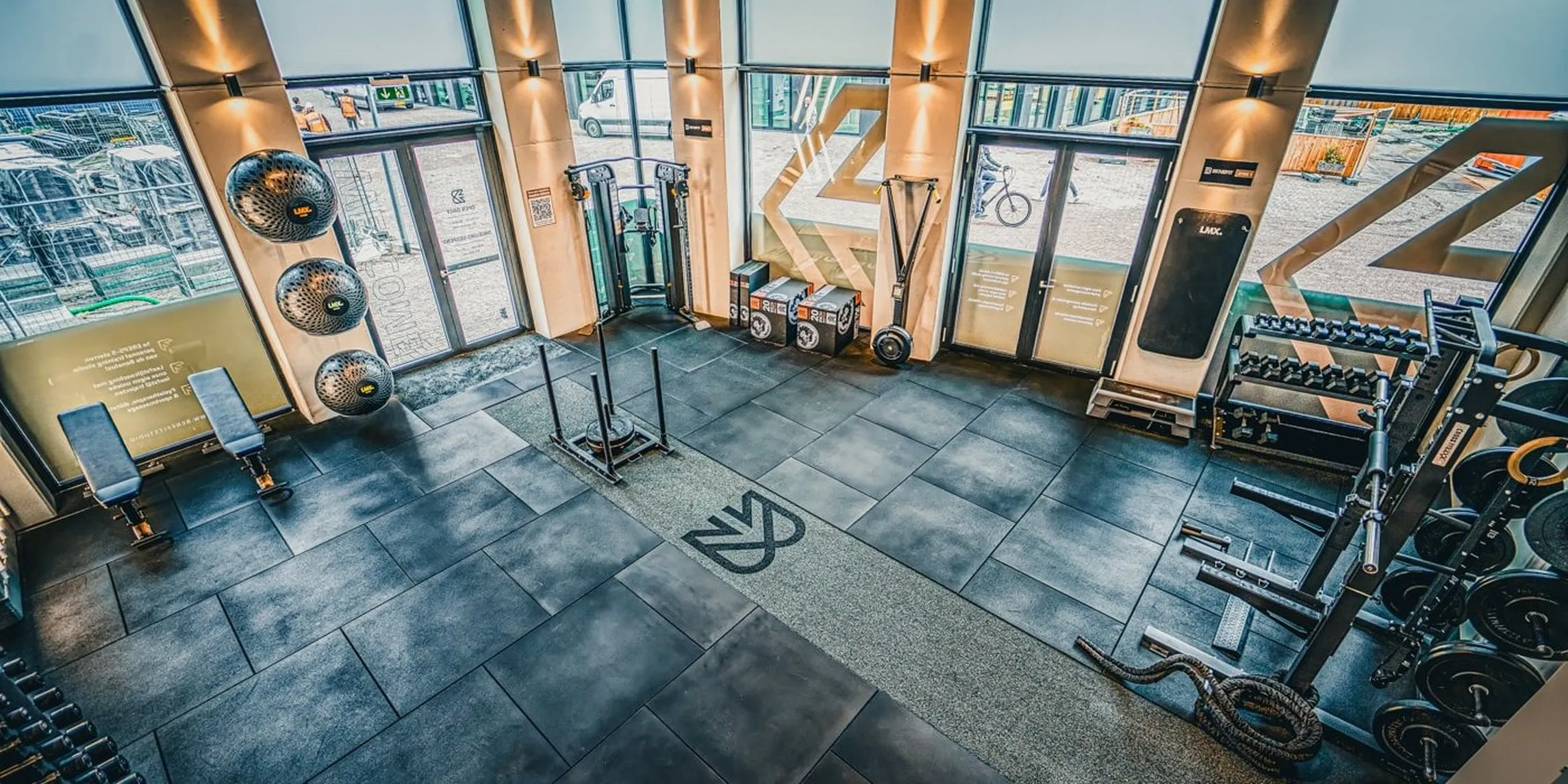 Trainingsruimte van BeneFIT Studio Den Haag City met racks en het beeldmerk op de vloer. Fotografie door Fitbrand