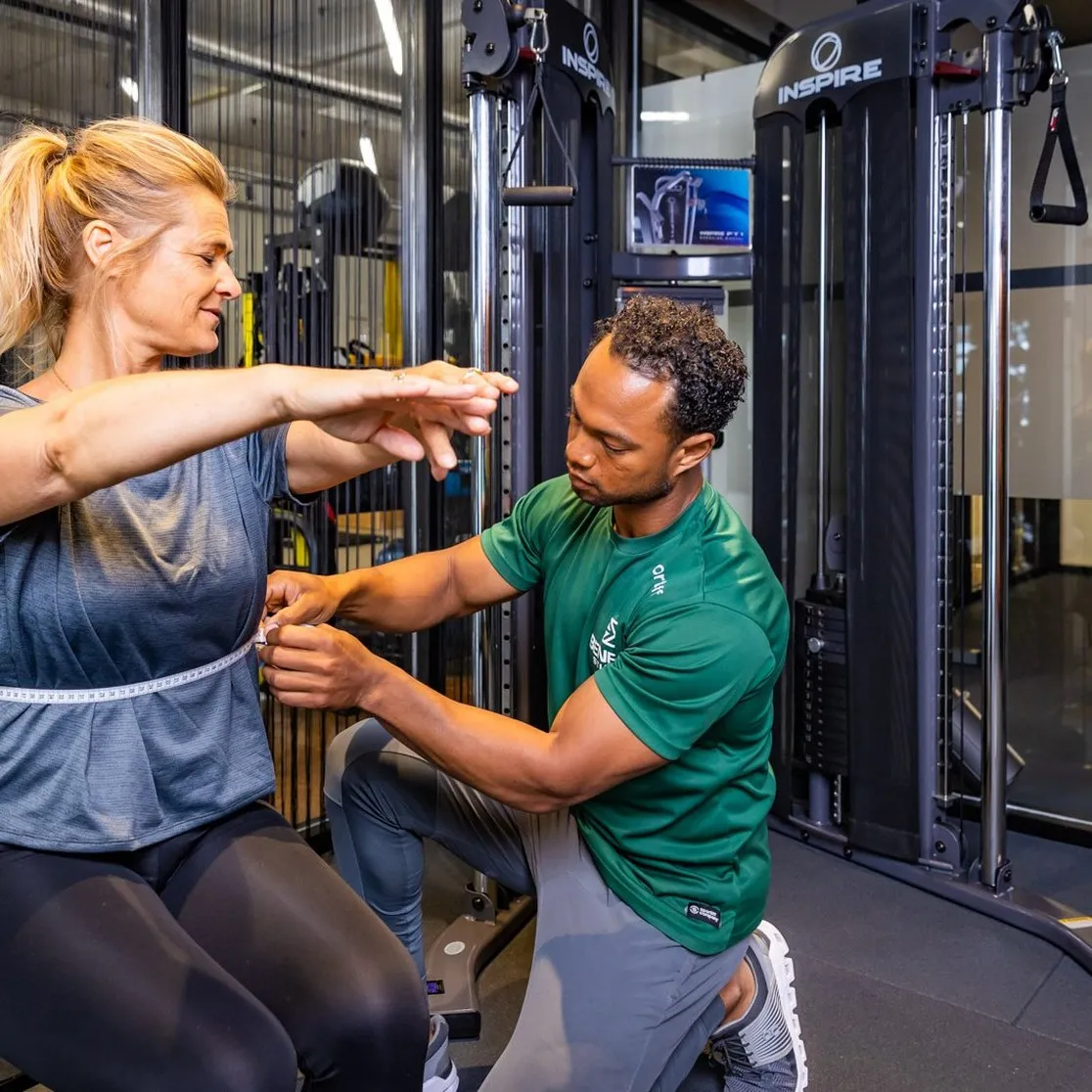 Personal trainer van BeneFIT Studio corrigeert de armhouding van een cliënt. Fotografie door Fitbrand