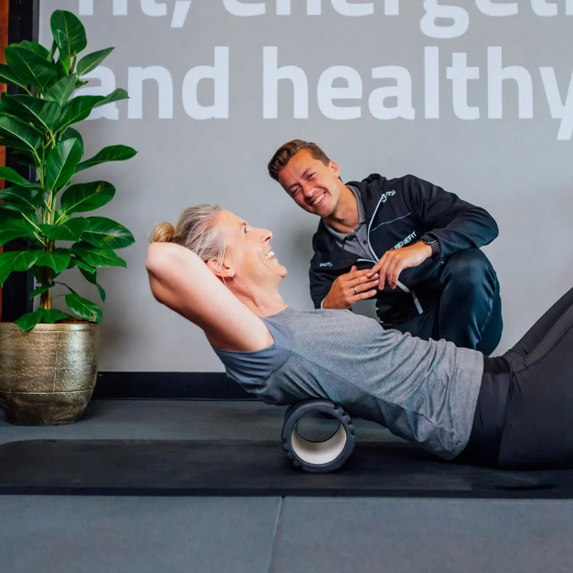 Cliënt rolt haar rug los op een foamroller met een personal trainer van BeneFIT Studio. Fotografie door Fitbrand