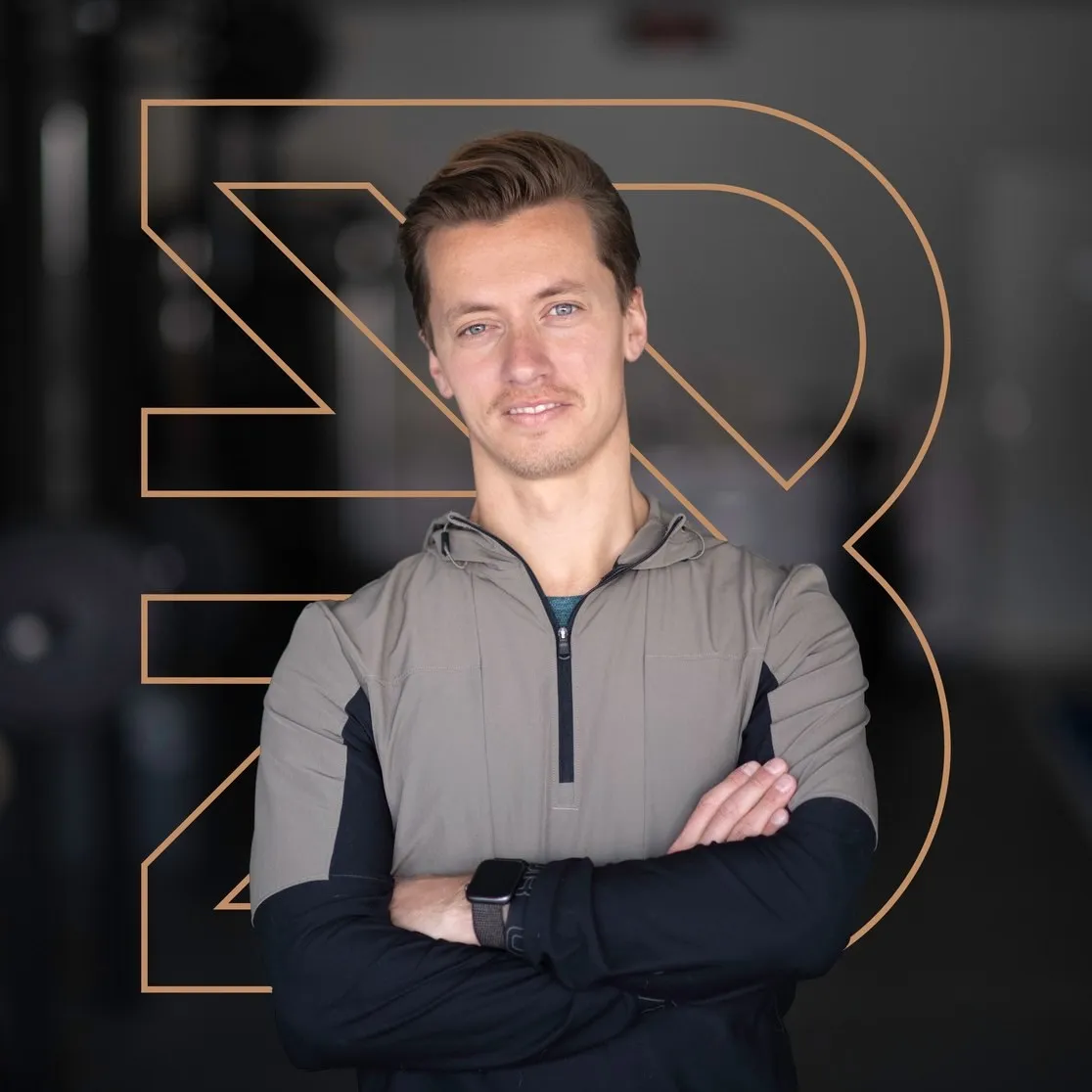 Personal trainer met gekruiste armen voor het koperen beeldmerk van BeneFIT Studio. Door Fitbrand
