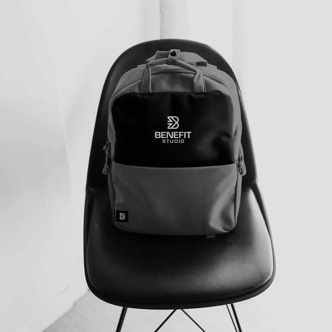 Zwart-grijze rugtas met het logo van BeneFIT Studio op een zwarte stoel. Door Fitbrand