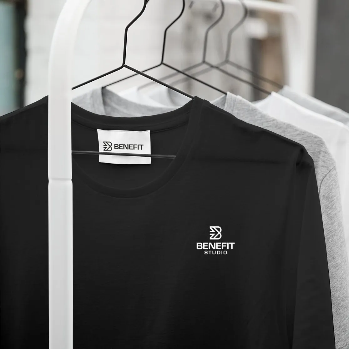 Zwarte en grijze shirts met het logo van BeneFIT Studio aan een kledingrek. Door Fitbrand