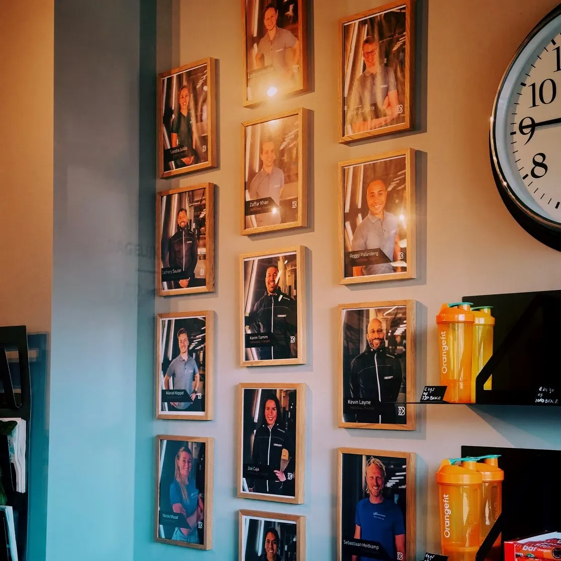 Wand in BeneFIT Studio Scheveningen met ingelijste portretten van de personal trainers. Fotografie door Fitbrand