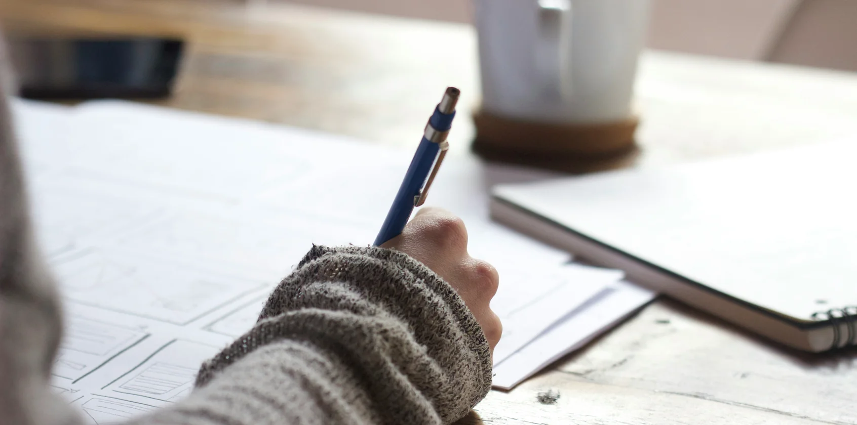 Iemand leest een geprinte opmaak mee aan tafel, pen in de hand